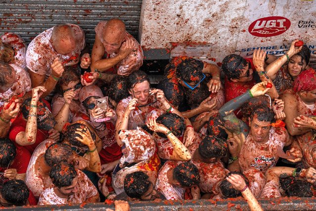 Revellers celebrate and throw tomatoes at each other as they participate in the annual Tomatina festival on August 30, 2023 in Bunol, Spain. Spain's tomato throwing party in the streets of Bunol, Valencia brings together almost 20,000 people, with some 150,000 kilos of tomatoes thrown each year, this year with a backdrop of high food prices affected by Spain's historic drought. (Photo by Zowy Voeten/Getty Images)