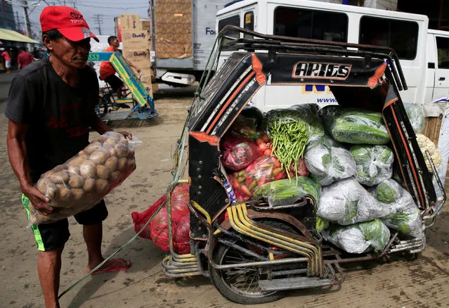 A worker unloads potatoes from his tricycle filled with vegetables as he delivers them to a wet market in Metro Manila, Philippines July 4, 2016. (Photo by Romeo Ranoco/Reuters)