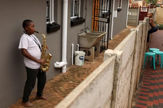 Ntsika Ntsele, 13, plays an alto saxophone while his neighbor looks on over a fence, during a nationwide lockdown for 21 days to try to contain the coronavirus disease (COVID-19) outbreak, in Soweto, South Africa, March 29, 2020. (Photo by Siphiwe Sibeko/Reuters)