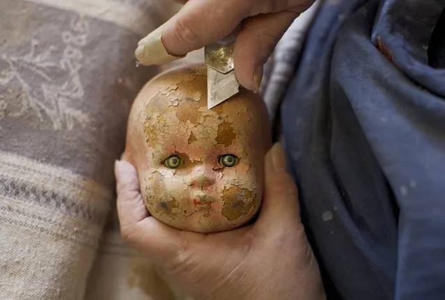 A badly-weathered composition doll, made from compressed wood chip, has its flakey paint cut off before being repaired and repainted by Gail Grainger, a 14-year veteran doll repairer at Sydney's Doll Hospital, August 19, 2014. (Photo by Jason Reed/Reuters)
