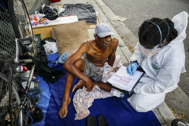 A worker talks with a homeless man before collecting a sample during a Miami-Dade County testing operation for the coronavirus disease (COVID-19), in downtown Miami, Florida, U.S., April 16, 2020. (Photo by Marco Bello/Reuters)
