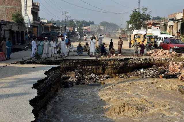 Residents gather beside a road damaged by flood waters following heavy monsoon rains in Charsadda district of Khyber Pakhtunkhwa on August 29, 2022. The death toll from monsoon flooding in Pakistan since June has reached 1,061, according to figures released on August 29, 2022, by the country's National Disaster Management Authority. (Photo by Abdul Majeed/AFP Photo)