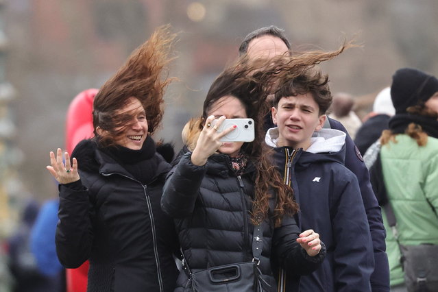 Members of the public attempt to take a selfie on Westminster bridge during wet and windy weather in Central London on New Year's Day on January 1, 2025. Yellow and amber weather warnings for wind, snow and rain are in place in parts of the United Kingdom. (Photo by George Cracknell Wright/The Times)