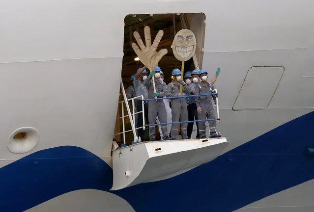 Crew on the the Ruby Princess wave with a cartoon sized hand and head as the ship departs from Port Kembla in Wollongong, Australia, Thursday, April 23, 2020. The ocean liner became notorious as Australia's largest single source of coronavirus infections and is the center of a criminal investigation over the sickness' spread set off a month after it was ordered by police to leave. (Photo by Rick Rycroft/AP Photo)