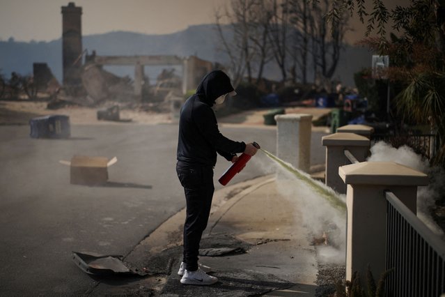 A resident tries to extinguish a smouldering fire on his house in the Palisades Highlands neighborhood on the west side of Los Angeles, on January 9, 2025. (Photo by Daniel Cole/Reuters)