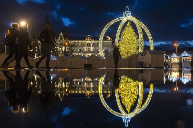Visitors walk in front of the illuminated Christmas tree at Cathedral Square in Vilnius, Lithuania, Monday, December 16, 2024. (Photo by Mindaugas Kulbis/AP Photo)