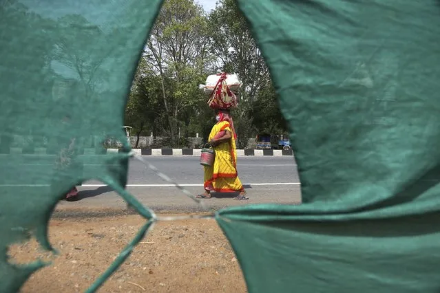 A migrant worker from Chhattisgarh state carries her belongings and makes the journey to her village hundreds of miles away on foot during a nationwide lockdown to curb the spread of new coronavirus in Hyderabad, India, Friday, May 8, 2020. Locking down the country's 1.3 billion people has slowed down the spread of the virus, but has come at the enormous cost of upending lives and millions of lost jobs. (Photo by Mahesh Kumar A./AP Photo)