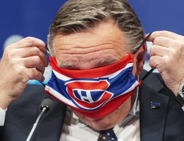 Quebec Premier Francois Legault puts on a Montreal Canadiens face mask as he finishes the daily COVID-19 press briefing, Thursday, May 21, 2020 in Montreal. (Photo by Ryan Remiorz/The Canadian Press via AP Photo)