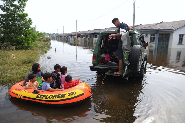 A vehicle pulls children in an inflatable boat through a flooded area in Pasir Mas, state of Kelantan, Malaysia, 03 December 2024. According to the National Disaster Control Center (NDCC), over 94,000 people have been displaced due to floods nationwide across nine states while six deaths have been recorded. Kelantan has been forecasted to face a second wave of floods on 04 December, according to the Kelantan state government on media social. (Photo by Fazry Ismail/EPA/EFE)