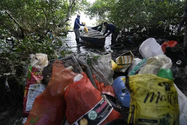 Fishermen carry garbage collected from the mangroves of Guanabara Bay in Rio de Janeiro, Brazil, Monday, June 13, 2022. Fishermen in the area are part of an environmental project supported by BVRio Institute and earn a salary collecting the garbage from the bay. (Photo by Silvia Izquierdo/AP Photo)