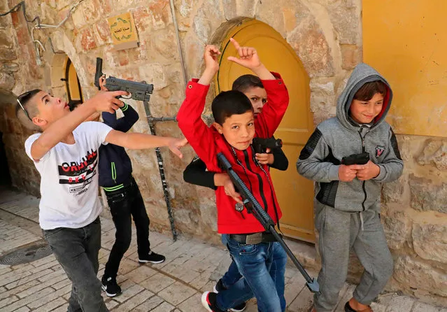 Palestinian children play with plastic toy guns as they celebrate on the first day of Eid al-Fitr, the Muslim holiday which starts at the conclusion of the holy fasting month of Ramadan, in the old city of the flashpoint city of Hebron in the occupied West Bank on May 24, 2020. (Photo by Hazem Bader/AFP Photo) 