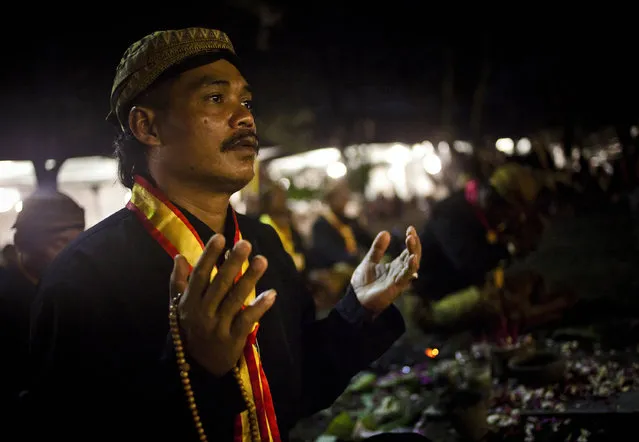 A Javanese man prays before rituals night carnival “1st Suro” ( Javanese calender) during  Islamic New Year celebrations at Kasunanan Palace on November 14, 2012 in Solo City, Central Java, Indonesia. Javanese will celebrate the national holiday with ceremonies and rituals marking the 1434th Islamic New Year's Eve or “1st Suro”. The parade started from Keraton Kasunanan and is headed by a group of albino buffaloes, known as Kebo Bule. Local people believe that the parade of Heirlooms and Kebo Bule will bring them a better life. (Photo by Ulet Ifansasti)