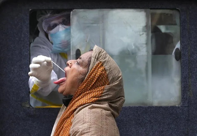 A woman reacts as a healthcare worker sitting inside an ambulance takes a swab from her to test for the coronavirus disease (COVID-19) in Kolkata, India, July 1, 2020. (Photo by Rupak De Chowdhuri/Reuters)