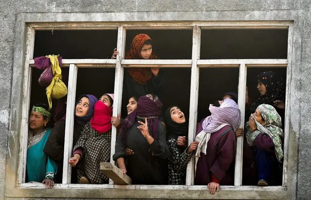 Indian Kashmiri villagers look out from a window during a funeral procession of a local militant Yawar Bashir at Hablish village of south Kashmirs Kulgam district on December 5, 2017. Three militants and an Indian army soldier were killed in a gunfight that erupted after militants attacked an army patrol on the Jammu-Srinagar highway in Bounigam area of Qazigund on December 4. Militants were caught alive in injured condition, officials said. (Photo by Tauseef Mustafa/AFP Photo)