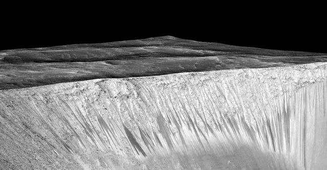 Dark narrow streaks called recurring slope lineae emanating out of the walls of Garni crater on Mars are seen in an image produced by NASA, Jet Propulsion Laboratory (JPL) and the University of Arizona. Scientists have found the first evidence that briny water may flow on the surface of Mars during the planet's summer months, a paper published on Monday showed. (Photo by Reuters/NASA/JPL/University of Arizona)