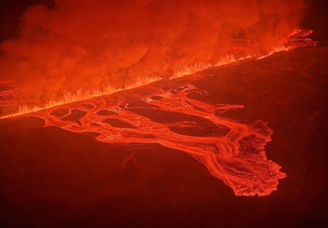 This handout picture released by the Icelandic Coast Guard on February 8, 2024 shows billowing smoke and flowing lava pouring out of a new fissure during a new volcanic eruption on the outskirts of the evacuated town of Grindavik, western Iceland. A volcanic eruption started on the Reykjanes peninsula in southwestern Iceland on Thursday, the third to hit the area since December, authorities said. (Photo by Icelandic Coast Guard/Handout via AFP Photo)