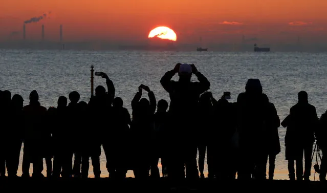 People watch the first sunrise on New Year's Day at a beach in Tokyo, Japan, January 1, 2018. (Photo by Toru Hanai/Reuters)