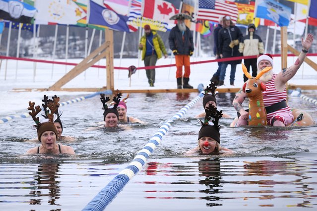 Swimmers, dressed as Santa and reindeer, take a lap during the 25 meter hat competition during the winter swimming festival on frozen Lake Memphremagog, Friday, February 23, 2024, in Newport, Vermont. (Photo by Charles Krupa/AP Photo)