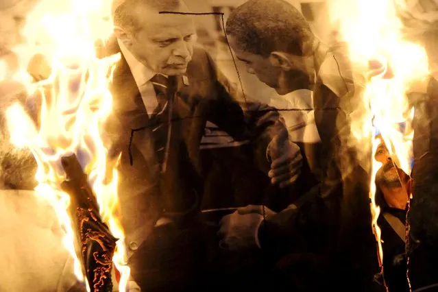 A protester is seen through a burning picture of Turkish President Tayyip Erdogan (L) and U.S President Barack Obama during a protest against Saturday's bombings in Ankara, in the northern city of Thessaloniki, Greece, October 12, 2015. Turkey's government said on Monday Islamic State was the prime suspect in suicide bombings that killed at least 97 people in Ankara, but opponents vented anger at President Tayyip Erdogan at funerals, universities and courthouses. (Photo by Alexandros Avramidis/Reuters)