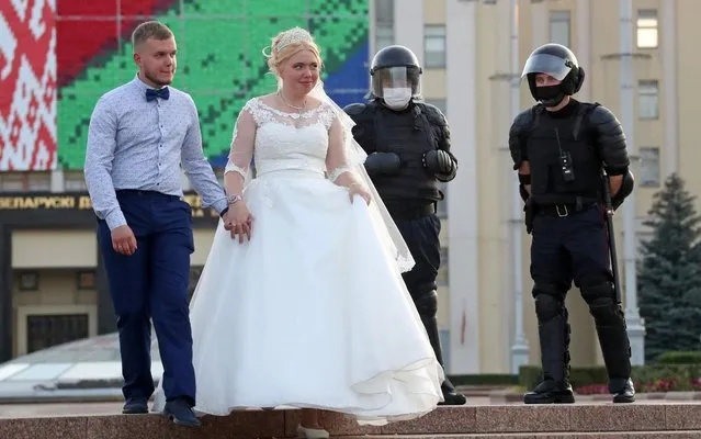 Newlyweds and police officers during a women's rally in Independence Avenue in Minsk, Belarus on September 5, 2020. Since the announcement of the 2020 Belarusian presidential election results on August 9, mass protests against the election results have been erupting in major cities across Belarus. (Photo by Valery Sharifulin/TASS)