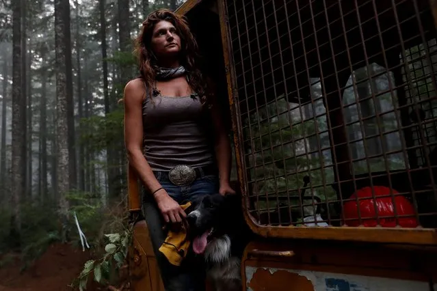 Nicole West stands for a portrait with her dog Oink on a bulldozer during the aftermath of the Riverside Fire near Molalla, Oregon, September 16, 2020. She was among 1,200 men and women of the “Hillbilly Brigade” who came together to fight the state's biggest fire in a century. They are credited with saving the mountain hamlet of Molalla, an hour's drive south of Portland, after its 9,000 residents were forced to evacuate. (Photo by Shannon Stapleton/Reuters)