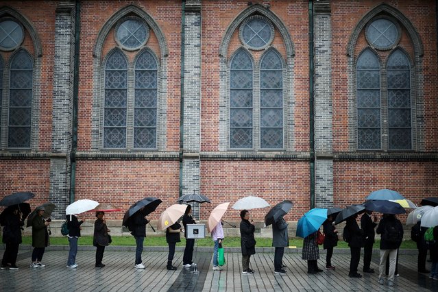 Catholic believers wait in a line to mourn Pope Francis as it rains at Myeongdong Cathedral in Seoul, South Korea, on April 22, 2025. (Photo by Kim Hong-Ji/Reuters)