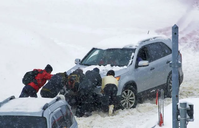 People push a vehicle in snow on a highway in Gangwon Province's Pyeongchang, about 126 kilometers (78 miles) east of Seoul, South Korea, Sunday, January 15, 2023. About 40 to 60 centimeters (16 to 23 inches) of snow fell in some areas in the eastern Gangwon regions. Elsewhere, on the Guri-Pocheon highway near the South Korean capital Sunday night, nearly 50 vehicles collided on an icy highway, killing at least one person and injuring dozens. (Photo by Yoo Hyung-je/Yonhap via AP Photo)