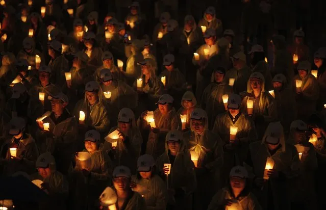 People hold candles during an event attempting to establish a Guinness World of Record for “Blowing out the most number of candles simultaneously” during Earth Hour in Shanghai March 23, 2013. Earth Hour, when everyone around the world is asked to turn off lights for an hour from 8.30 p.m. local time, is meant as a show of support for tougher action to confront climate change. (Photo by Carlos Barria/Reuters)