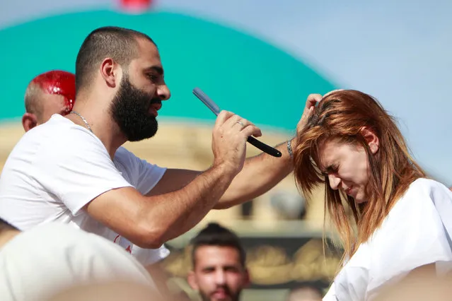 A Shi'ite Muslim attempts to tap the head of a woman with a razor to draw blood during a religious procession to mark Ashura in Nabatiyeh town, southern Lebanon, October 12, 2016. (Photo by Ali Hashisho/Reuters)