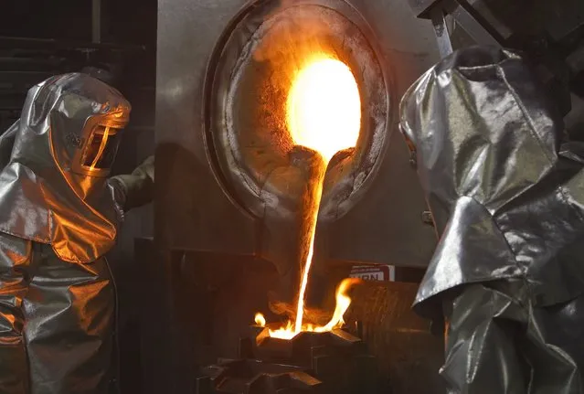 Workers in protective suits pour out the melted gold of a crucible in forms. March 14, 2013; Tien Shan mountains, Kyrgyzstan. (Photo by Shamil Zhumatov/Reuters)