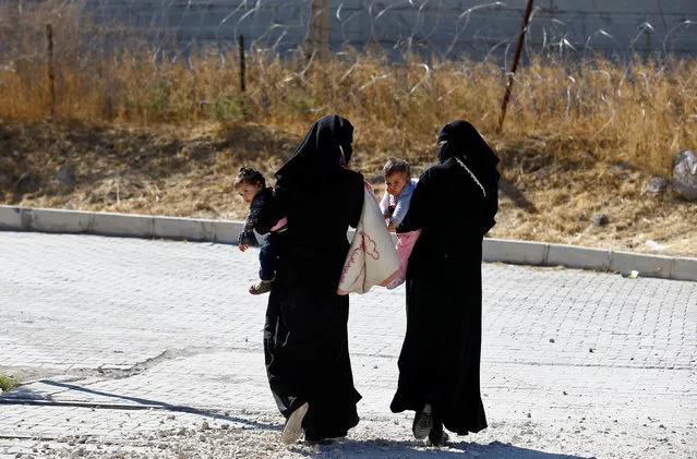 Syrian women carrying their babies walk through the border gate to cross the Syrian town of Jarablus, in Karkamis, Turkey, October 19, 2016. (Photo by Umit Bektas/Reuters)