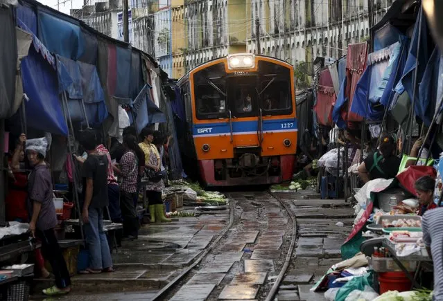 Thai vegetable market vendors pull back awnings and their produce off a railway track to allow a cross-country train to dissect through the middle of the town of Maeklong, in Samut Songkhram province, 60 km (37 miles) west of Bangkok in this August 16, 2012 file photo. (Photo by Chaiwat Subprasom/Reuters)