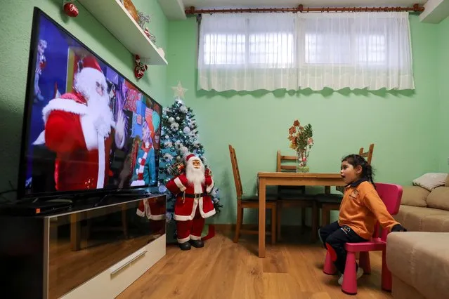 Arhoa Pena, 3, reacts as she watched a personalized Christmas video message recorded by artist Hector Fuentes dressed up as Santa Claus, and his companion artist Pilar Carrion dressed up as an elf, at her home in Alcorcon, near Madrid, Spain, December 18, 2020. (Photo by Sergio Perez/Reuters)