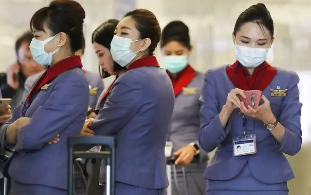A flight crew from China Airlines, wearing protective masks, stand in the international terminal after arriving on a flight from Taipei at Los Angeles International Airport (LAX) on February 28, 2020 in Los Angeles, California. The World Health Organization (WHO) has raised the global coronavirus risk level to “very high”. (Photo by Mario Tama/Getty Images)