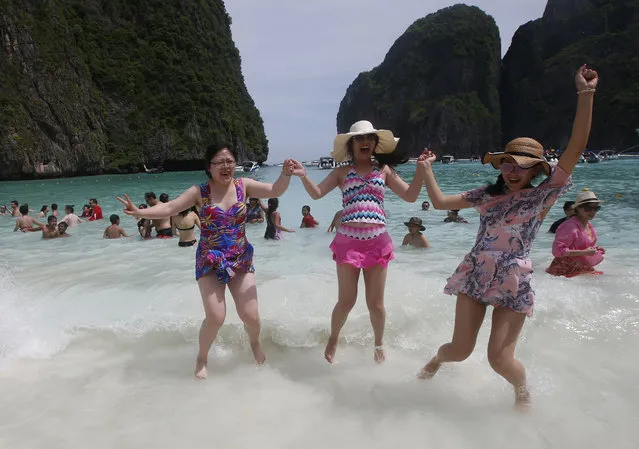 Tourists jump in the waves on Maya Bay, Phi Phi Leh island in Krabi province, Thailand, Thursday, May 31, 2018. The popular tourist destination of Maya Bay in the Andaman Sea will close to tourists for four months from Friday to give its coral reefs and sea life a chance to recover from an onslaught that began nearly two decades ago. (Photo by Sakchai Lalit/AP Photo)