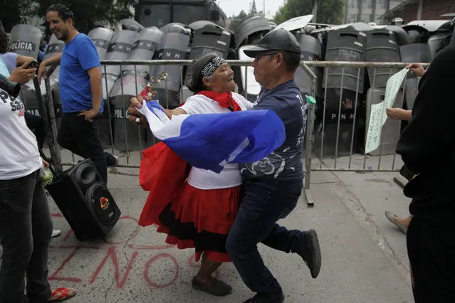 A couple dances in front of the police barricade during a protest in Tegucigalpa, Honduras, Saturday June 2, 2018. Members of the Opposition Alliance Against the Dictatorship marched the streets in protest of Juan Orlando Hernandez' government and were forcibly removed by military and police. (Photo by Fernando Antonio/AP Photo)