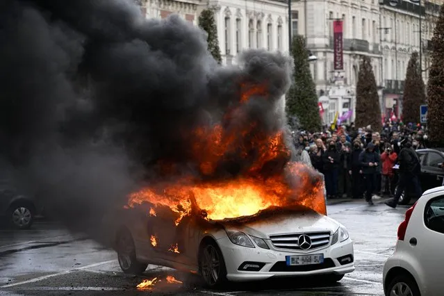 Flames rise from a Mercedes car set on fire during a demonstration on the 12th day of action after the government pushed a pensions reform through parliament without a vote, using the article 49.3 of the constitution, in Rennes, northwestern France on April 13, 2023. France faced nationwide protests and strikes on April 13, 2023, to denounce the French government's pension reform on the eve of a ruling from France's Constitutional Council on the reform. (Photo by Damien Meyer/AFP Photo)