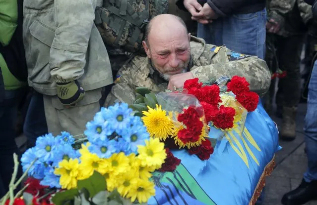 A comrade cries during the funeral ceremony for servicemen Sergey Kochetov and Nikolay Sayuk, Ukrainian volunteers from “Aydar Battalion” who were killed in a war conflict in eastern Ukraine, at the Independence Square in Kiev, Ukraine, Friday, November 4, 2016. Pro-Russian separatists attacked Ukrainian army positions in eastern Ukraine 31 times in the past 24 hours, officials said. (Photo by Efrem Lukatsky/AP Photo)