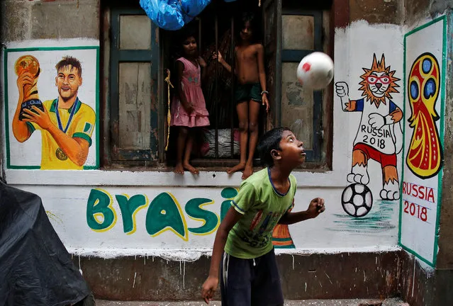 A boy plays in front an image of Brazil's soccer player Neymar painted on a wall in an alley at a slum area, ahead of the FIFA World Cup, in Kolkata, June 7, 2018. (Photo by Rupak De Chowdhuri/Reuters)