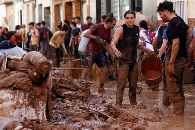 Volunteers clean as the street is covered in mud in the aftermath of torrential rains that caused flooding, in Paiporta, Spain on November 1, 2024. (Photo by Eva Manez/Reuters)