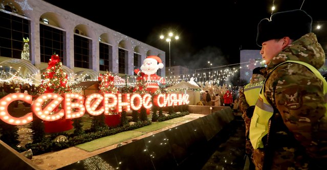 Soldiers stand guard as people gather in front of an illuminated Christmas tree and other decorations on the central Ala-Too square during the official Christmas tree lighting ceremony in Bishkek, Kyrgyzstan, 14  December 2024. (Photo by Igor Kovalenko/EPA/EFE)