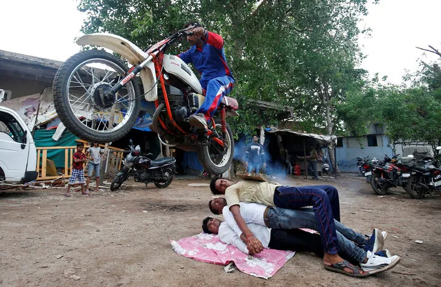 A Hindu devotee performs a stunt with his motorcycle during rehearsals ahead of the annual Rath Yatra, or chariot procession, in Ahmedabad, India, July 3, 2018. (Photo by Amit Dave/Reuters)