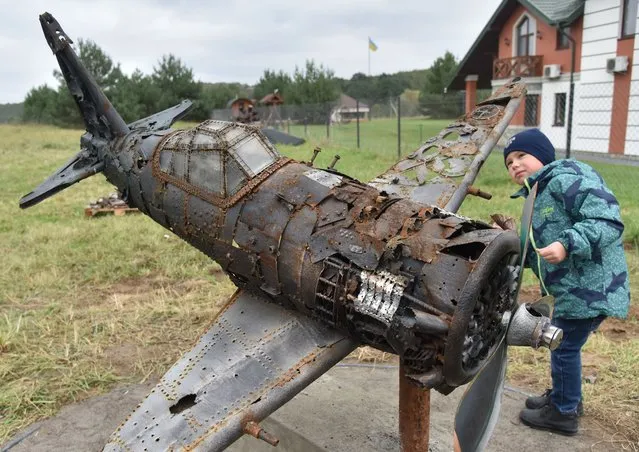 A young visitor looks at the model of a plane made from scrap metal parts of different WW II era planes and part of a museum exhibition in the village of Khorosno, near Lviv, Ukraine, 01 November 2020. The museum of dead planes was opened on 01 November and presents wreckage of a dozen Second World War planes found in Western Ukraine by enthusiasts. (Photo by Pavlo Palamarchuk/EPA/EFE)