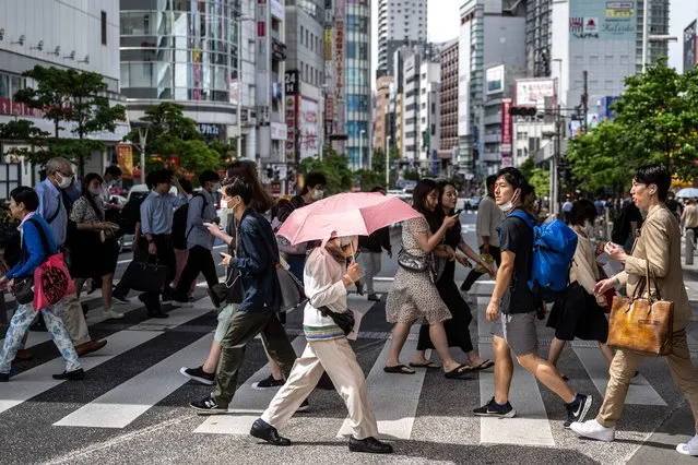 Pedestrians cross a street in the Shinjuku district of Tokyo on June 1, 2023. (Photo by Philip Fong/AFP Photo)