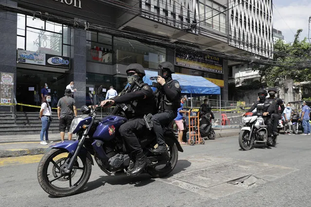 Philippine police patrol outside the Malate Bayview Mansion that was placed under lockdown due to the number of COVID-19 cases among residents in Manila, Philippines on Thursday, March 11, 2021. (Photo by Aaron Favila/AP Photo)