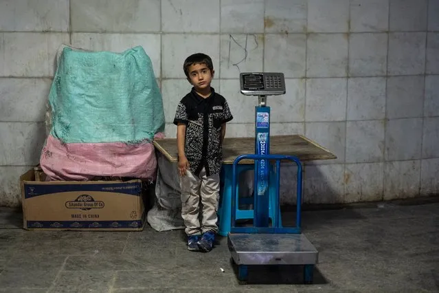 An Afghan boy stands besides a weighing machine while waiting for customers to measure their weight for a fee at an underground walkway in Kabul on June 27, 2023. (Photo by Wakil Kohsar/AFP Photo)