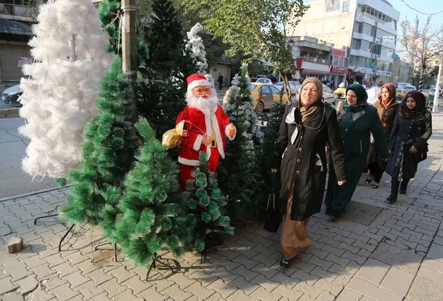 Iraqis pass by a shop selling Christmas decorations in the Karrada neighborhood of Baghdad, Iraq, Thursday, December 24, 2015. Christians around the world will celebrate Christmas on Friday. (Photo by Karim Kadim/AP Photo)