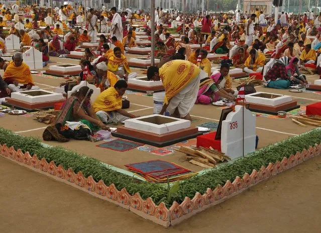 Hindu priests and devotees sit around decorated "havan kunds" or a sacred pits in which fire is lit and offerings are made, as they pray on the first day of the five-day long mass prayer meetings for the world peace at a temple on the outskirts of Ahmedabad, India, December 23, 2015. (Photo by Amit Dave/Reuters)