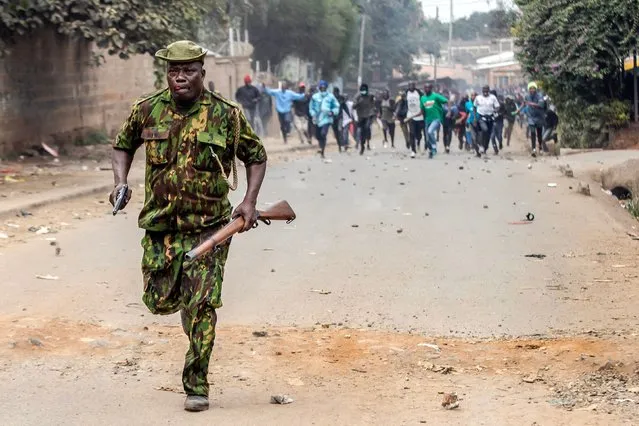 A Kenya Police Officer runs away from a group of opposition supporters chasing him and throwing stones during anti-government protests in Nairobi on July 19, 2023. Kenya braced on July 19, 2023 for a new round of protests despite the government warning it would not tolerate further unrest after earlier demonstrations turned violent with more than a dozen people killed. (Photo by Luis Tato/AFP Photo)