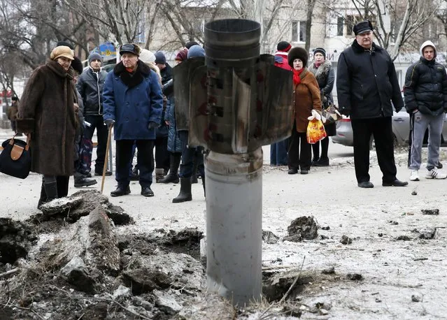 People look at the remains of a rocket shell on a street in the town of Kramatorsk, eastern Ukraine February 10, 2015. (Photo by Gleb Garanich/Reuters)